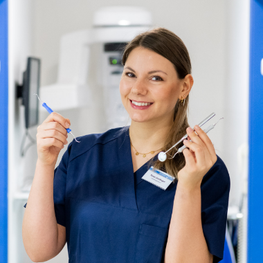 Dentalhygienikerin in moderner Zahnarztpraxis hält Instrumente für professionelle Zahnreinigung (PZR).